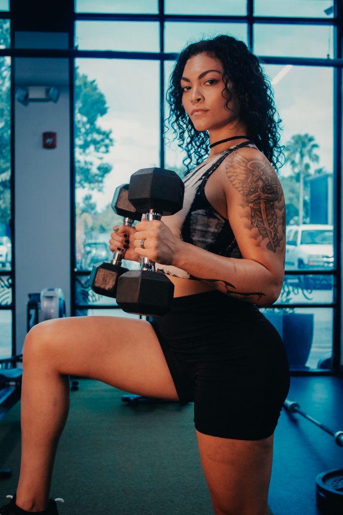 Fit woman exercising with dumbbells indoors, showcasing strength and determination.